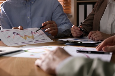 Photo of Business people working with charts and graphs at table in office, closeup. Investment analysis