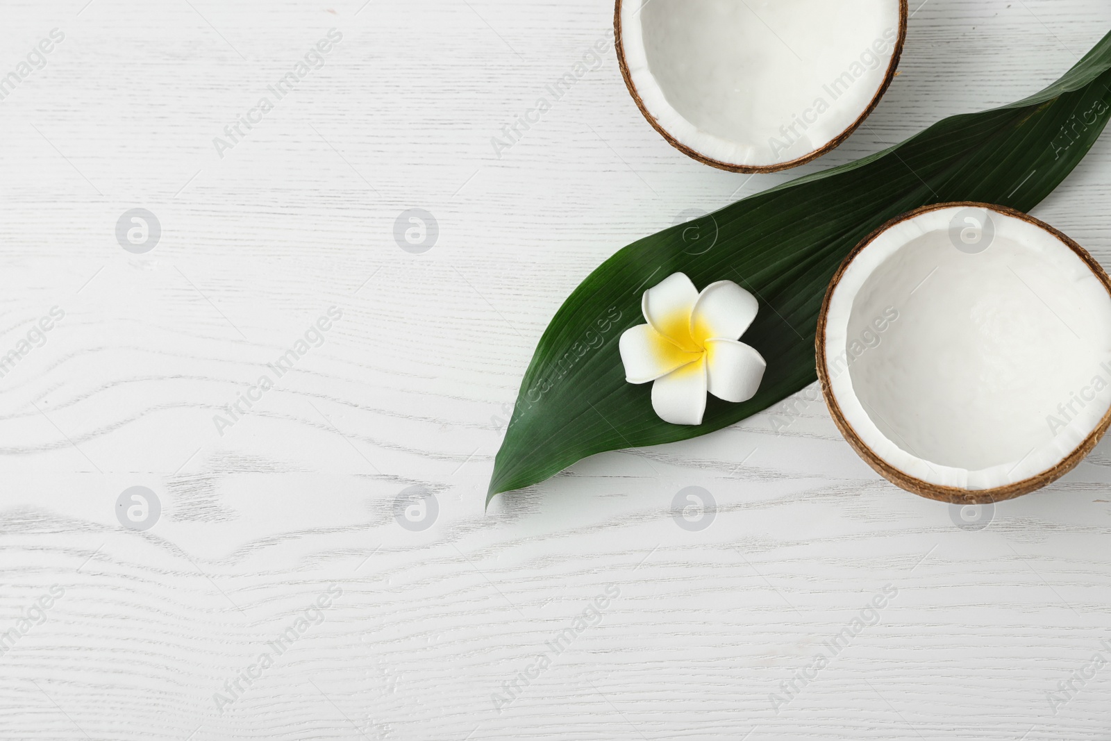 Photo of Flat lay composition with halves of coconut on white wooden background. Space for text