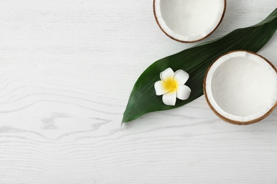 Photo of Flat lay composition with halves of coconut on white wooden background. Space for text