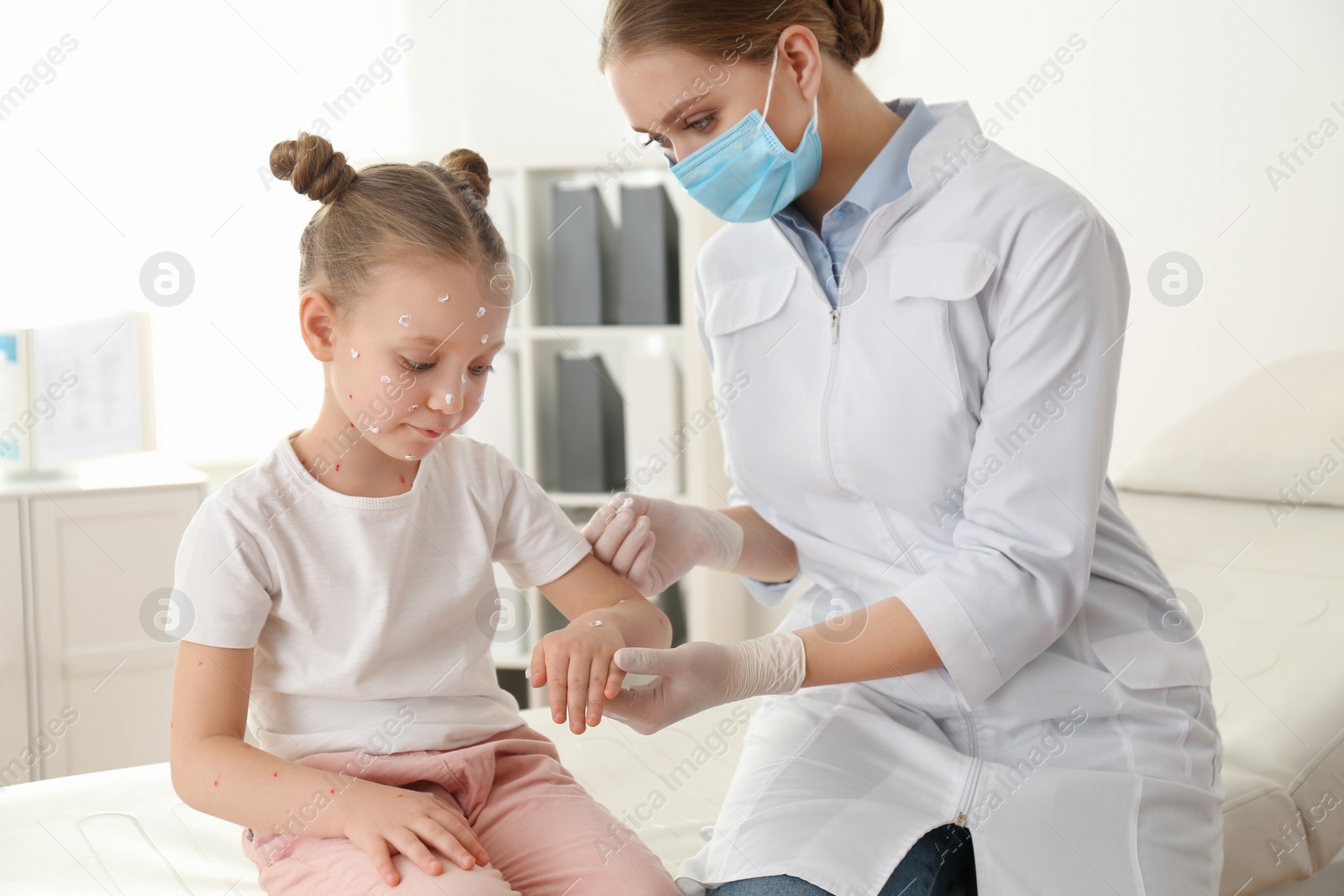 Photo of Doctor applying cream onto skin of little girl with chickenpox in clinic. Varicella zoster virus
