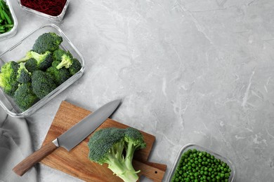 Photo of Wooden board, broccoli, knife and containers with fresh products on light gray marble table, flat lay with space for text. Food storage