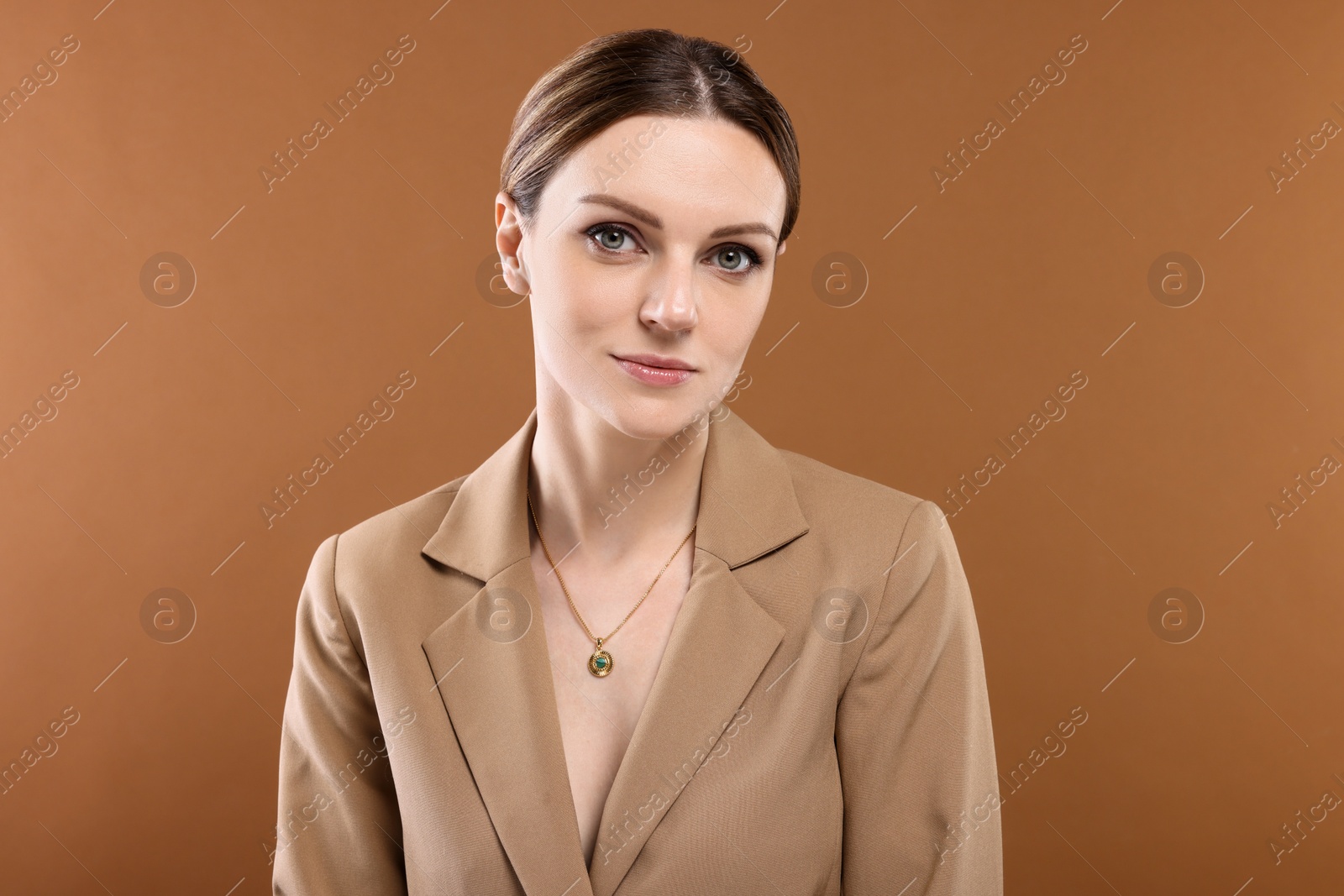 Photo of Beautiful woman with elegant necklace on brown background