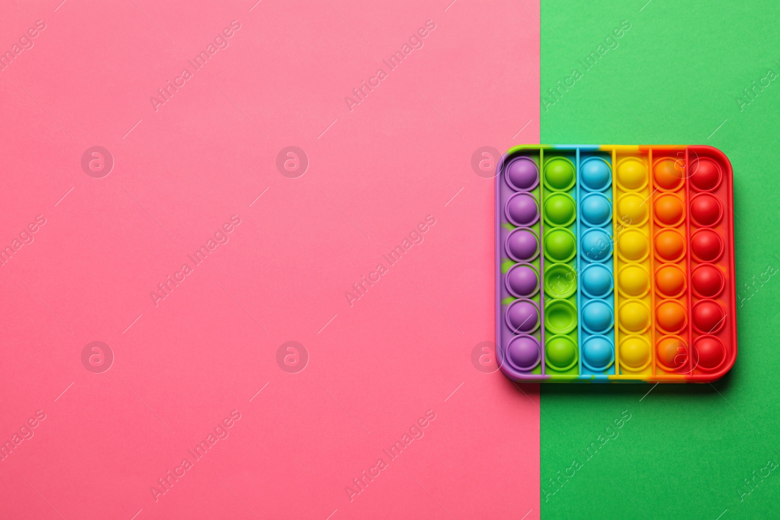 Photo of Rainbow pop it fidget toy on color background, top view. Space for text