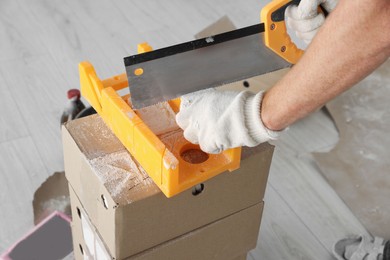 Photo of Worker cutting decorative bricks with saw indoors, closeup