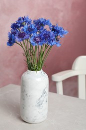 Photo of Bouquet of beautiful cornflowers in vase on light table at home.