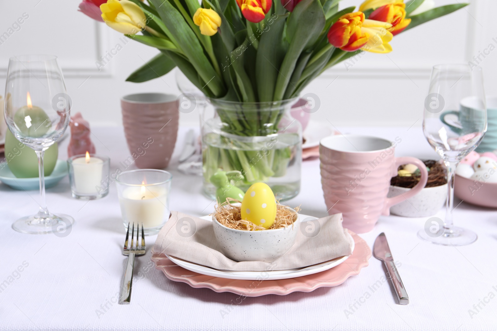 Photo of Festive table setting with painted egg in decorative nest. Easter celebration