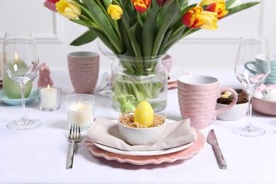 Festive table setting with painted egg in decorative nest. Easter celebration