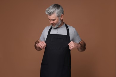Photo of Man wearing kitchen apron on brown background. Mockup for design