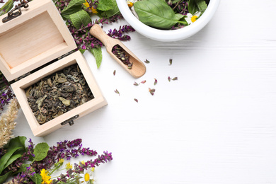 Flat lay composition with mortar, box and healing herbs on white wooden table, space for text