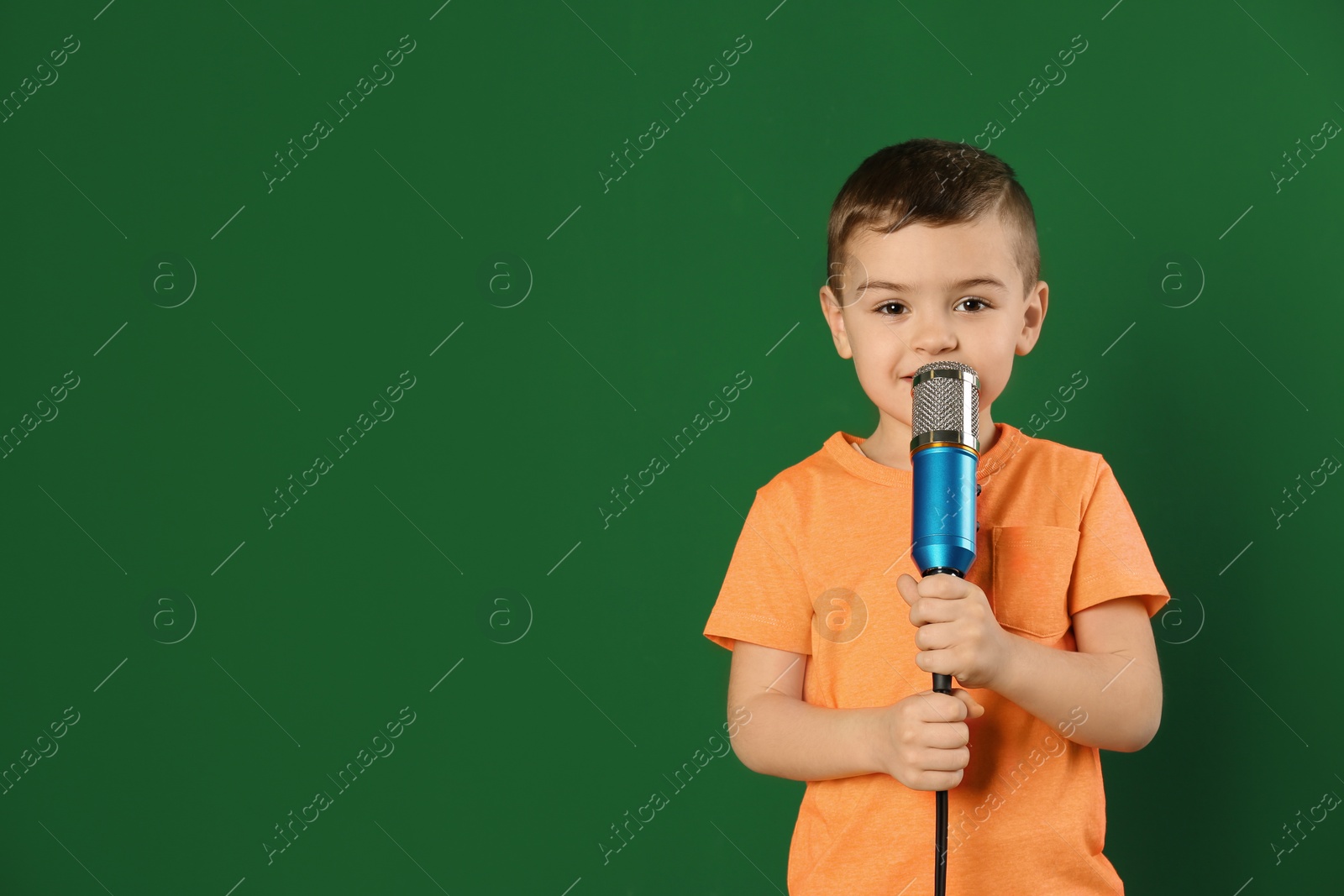 Photo of Cute funny boy with microphone on color background. Space for text