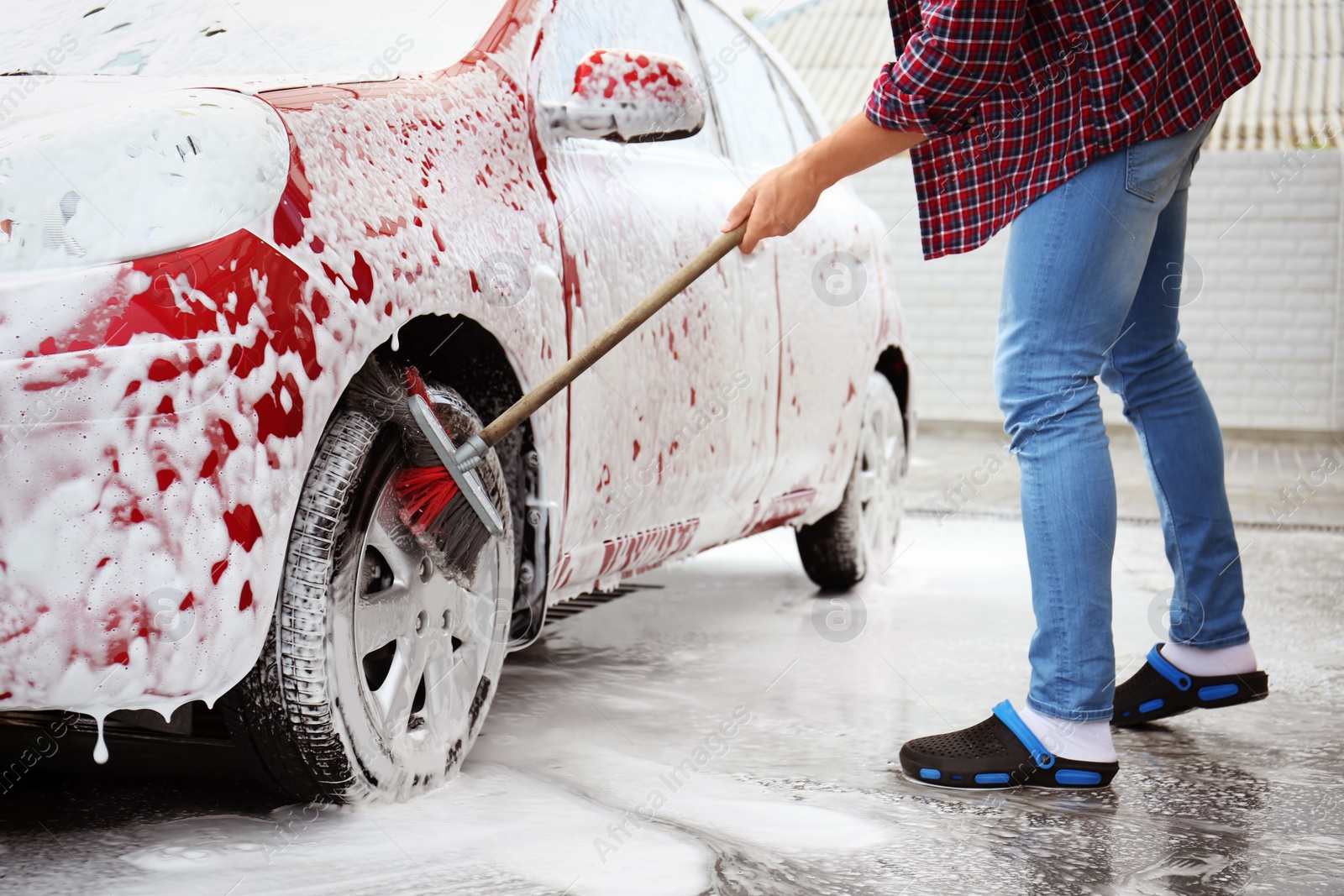 Photo of Young man cleaning vehicle with brush at self-service car wash