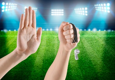 Image of Referee holding whistle and showing stop gesture at stadium, closeup