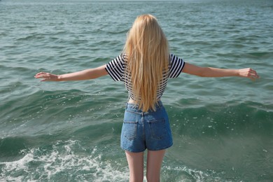 Photo of Young woman near sea on sunny day in summer, back view