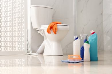 Photo of Cleaning supplies near toilet bowl in modern bathroom