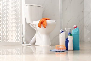 Cleaning supplies near toilet bowl in modern bathroom