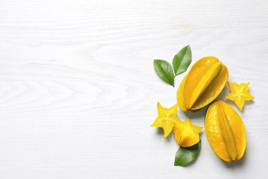 Photo of Delicious carambola fruits on white wooden table, flat lay. Space for text