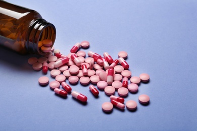 Photo of Bottle with vitamin pills and capsules on color background