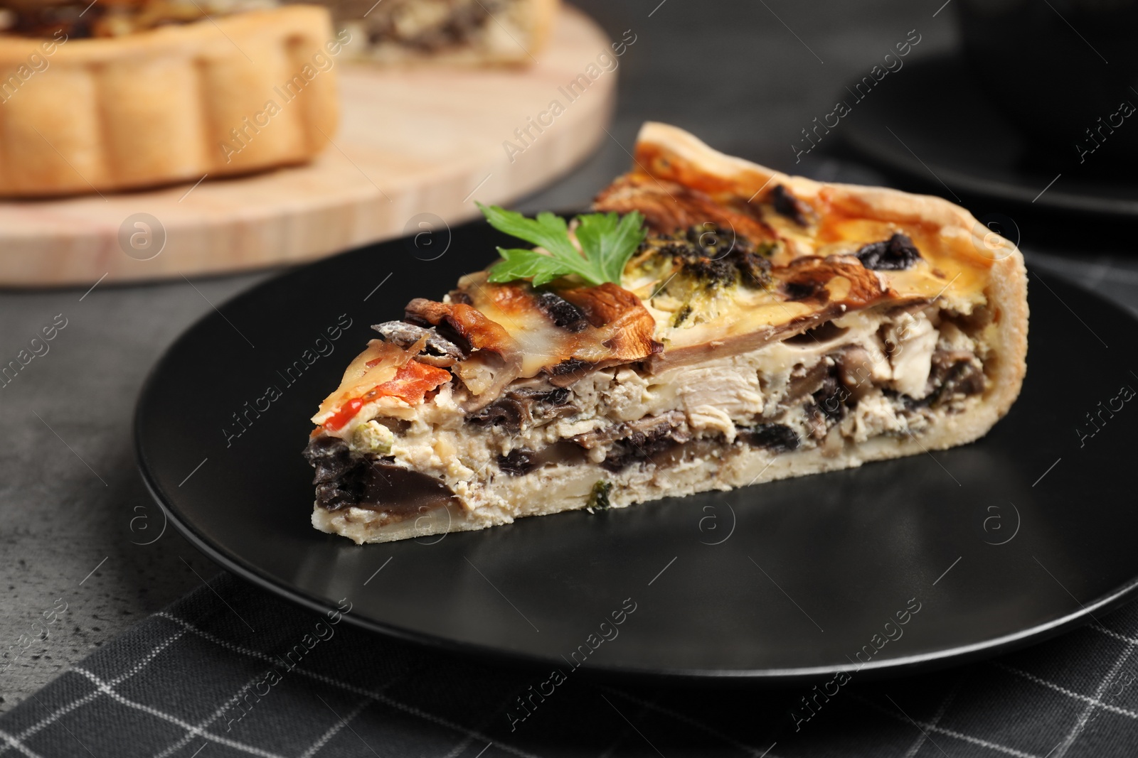 Photo of Piece of delicious quiche with mushrooms on grey table, closeup
