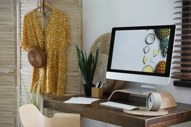 Photo of Comfortable workplace near window with horizontal blinds in room