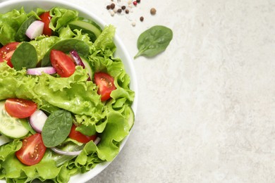 Photo of Delicious salad in bowl on light grey table, top view. Space for text