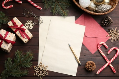 Photo of Flat lay composition with blank sheets of paper on wooden table, space for text. Writing letter to Santa