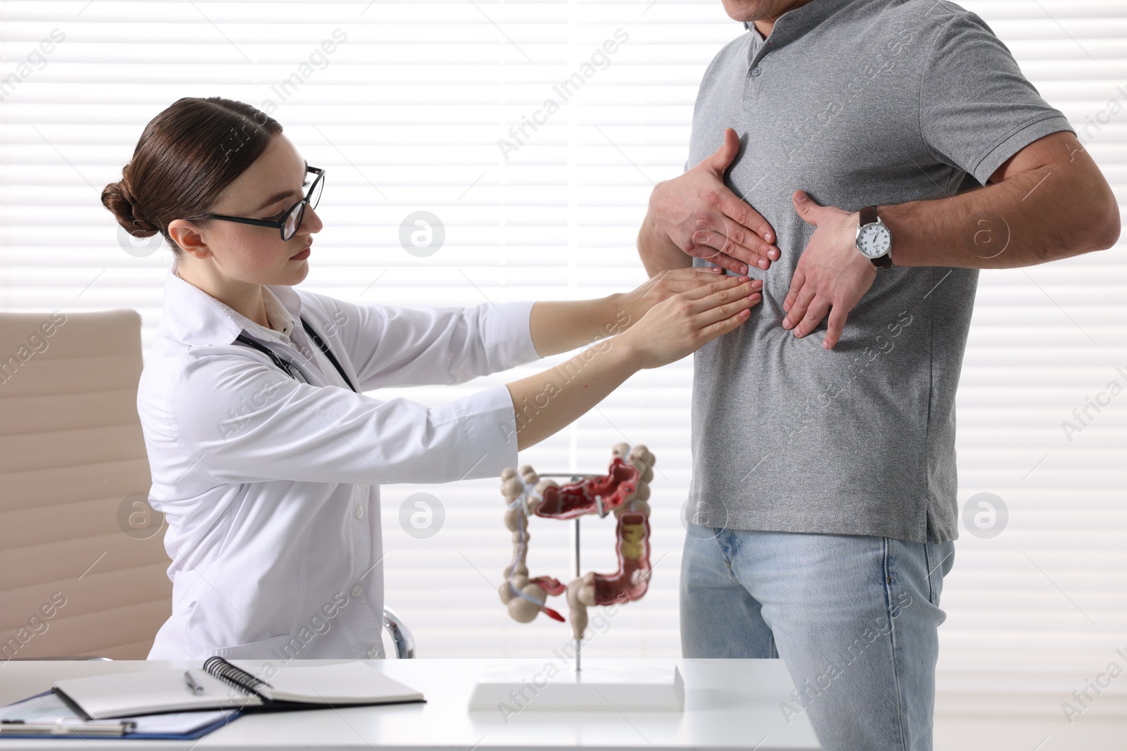 Photo of Gastroenterologist examining patient with stomach pain in clinic