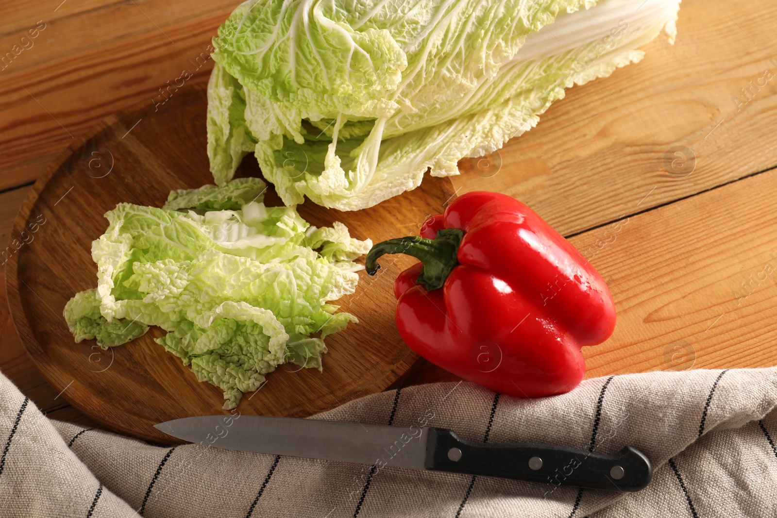 Photo of Fresh Chinese cabbage, pepper and knife on wooden table, above view