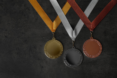 Photo of Gold, silver and bronze medals on grey stone background, flat lay. Space for design
