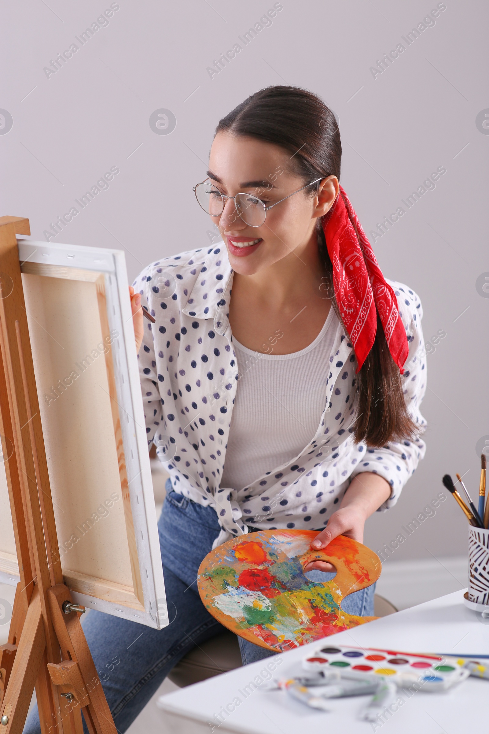 Photo of Happy woman artist drawing picture on canvas indoors