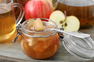 Photo of Delicious apple jam in jar on wooden table, closeup