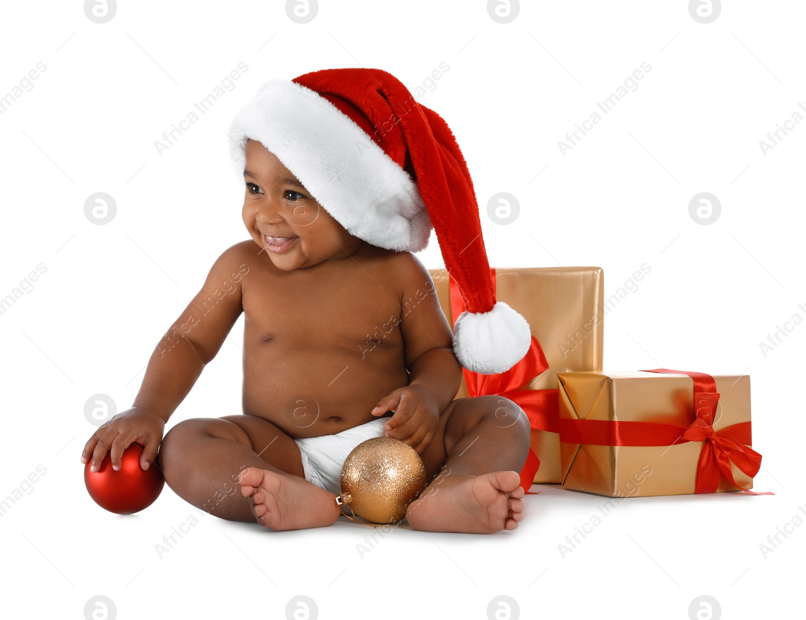 Photo of Cute African-American baby wearing Santa hat with Christmas gifts on white background