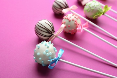 Photo of Different tasty cake pops on pink background