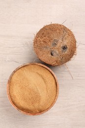 Coconut sugar in bowl and fruit on light wooden table, top view