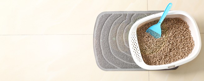 Image of Cat tray with biodegradable litter and scoop on floor, top view. Banner design with space for text