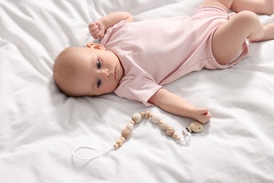 Photo of Cute little baby with toy lying on white sheets