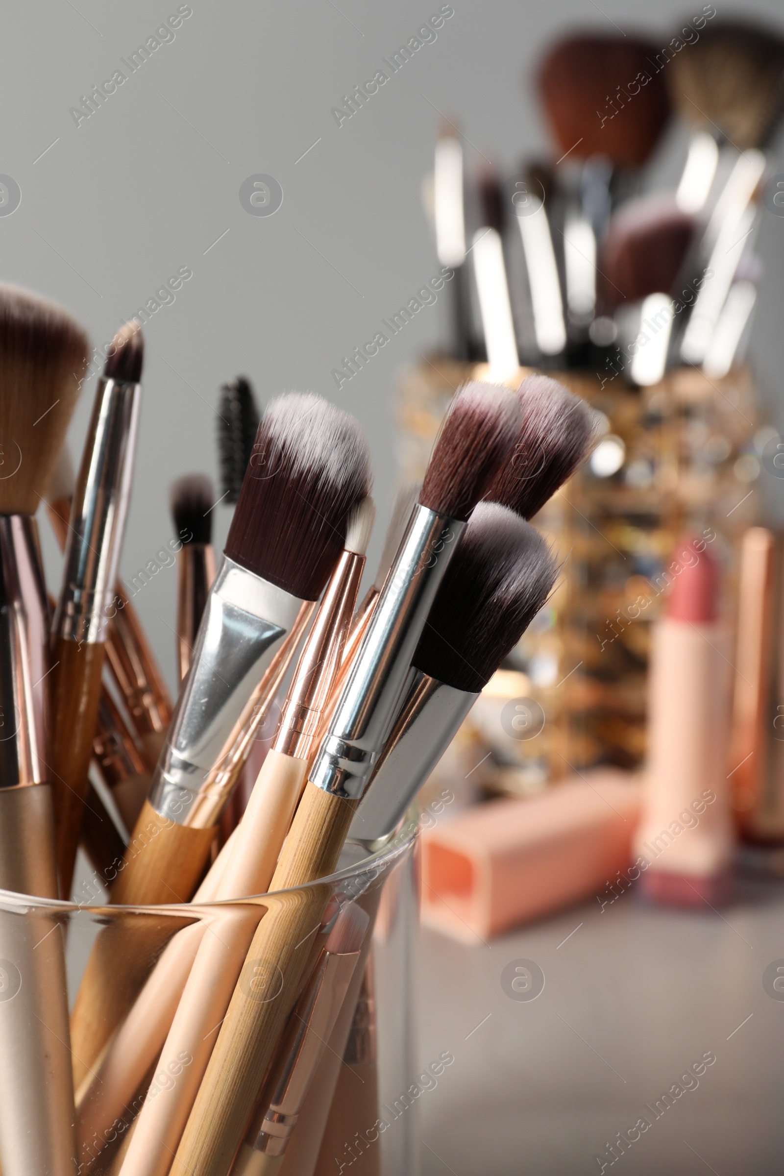 Photo of Set of professional makeup brushes on grey table, closeup