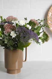Ceramic vase with beautiful bouquet on light table near white brick wall