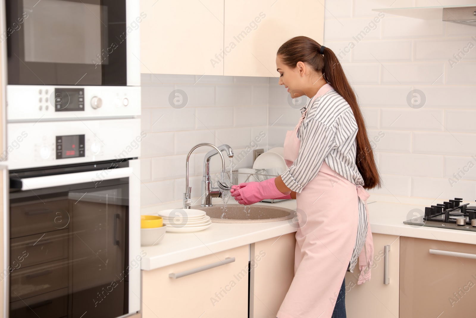 Photo of Woman doing washing up in kitchen. Cleaning chores