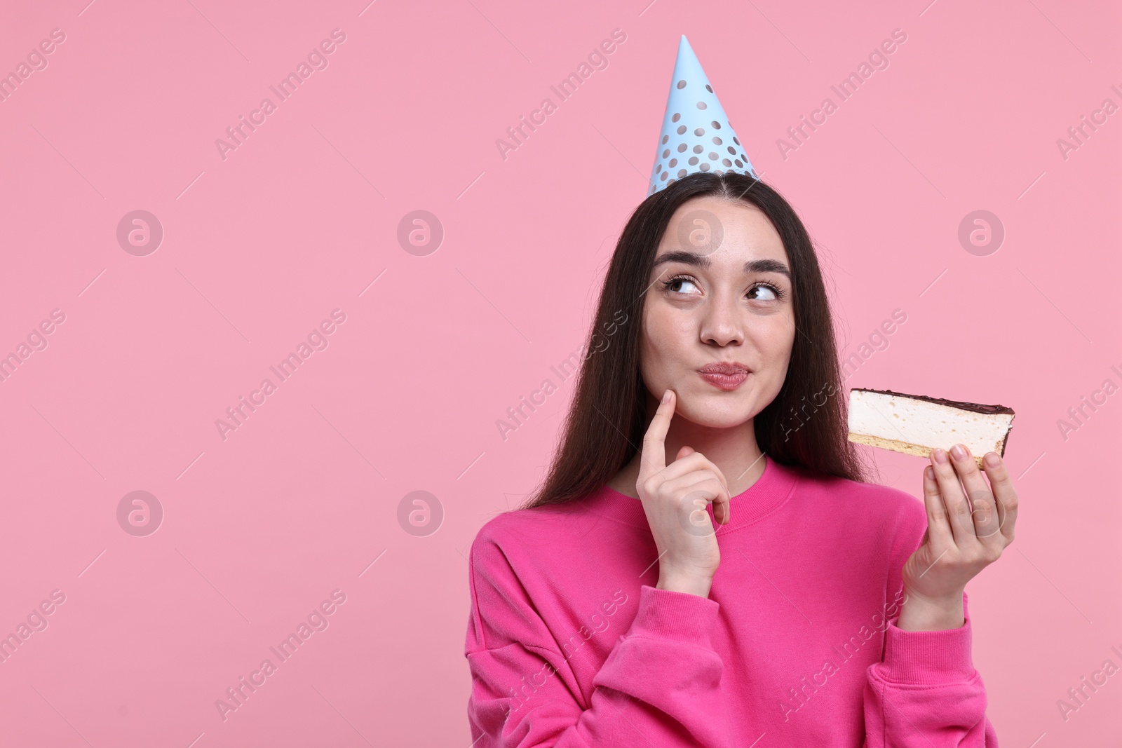 Photo of Woman in party hat with piece of tasty cake on pink background, space for text