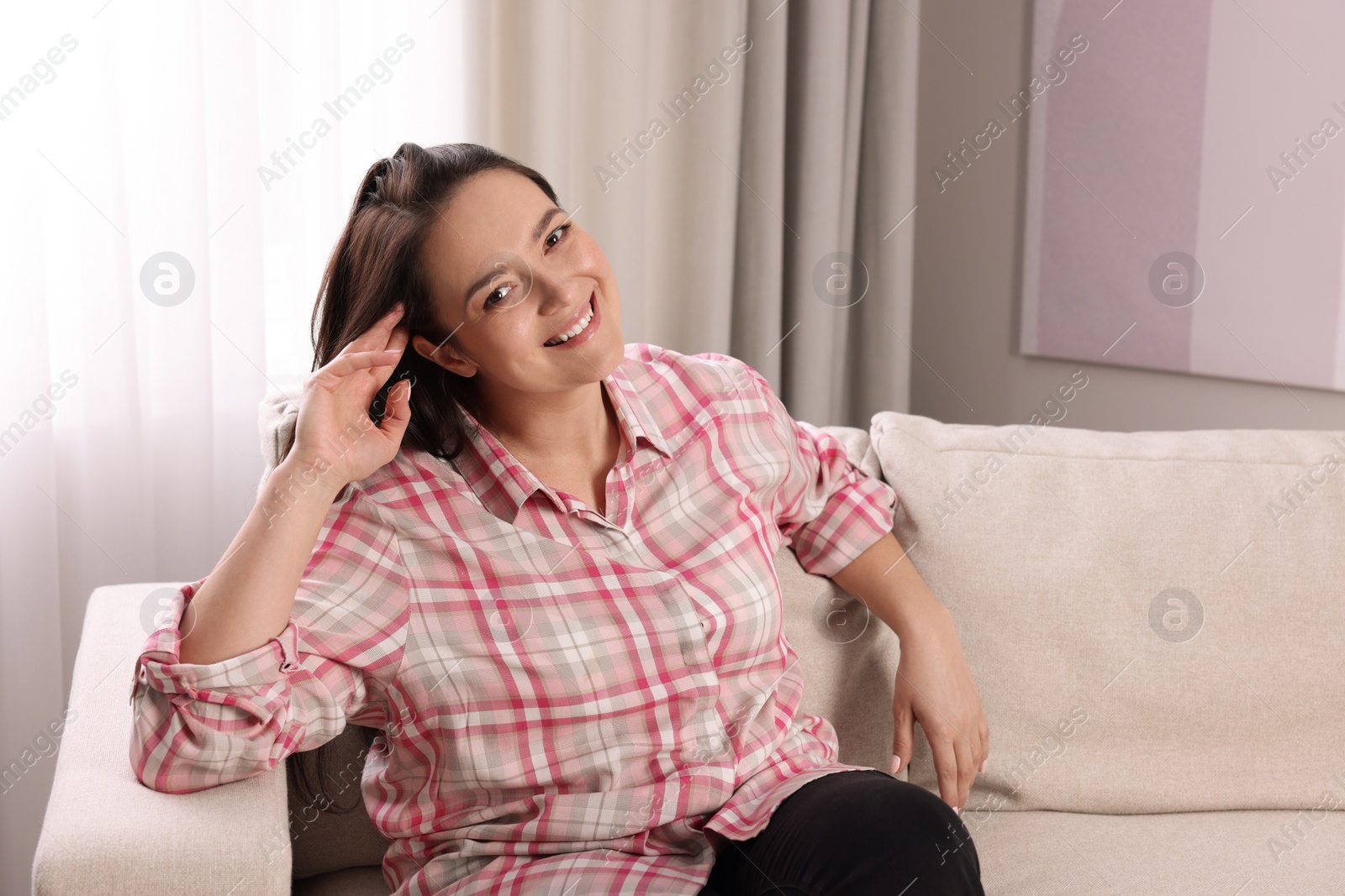 Photo of Beautiful overweight woman sitting on sofa at home