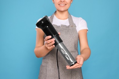 Woman holding sous vide cooker on light blue background, closeup
