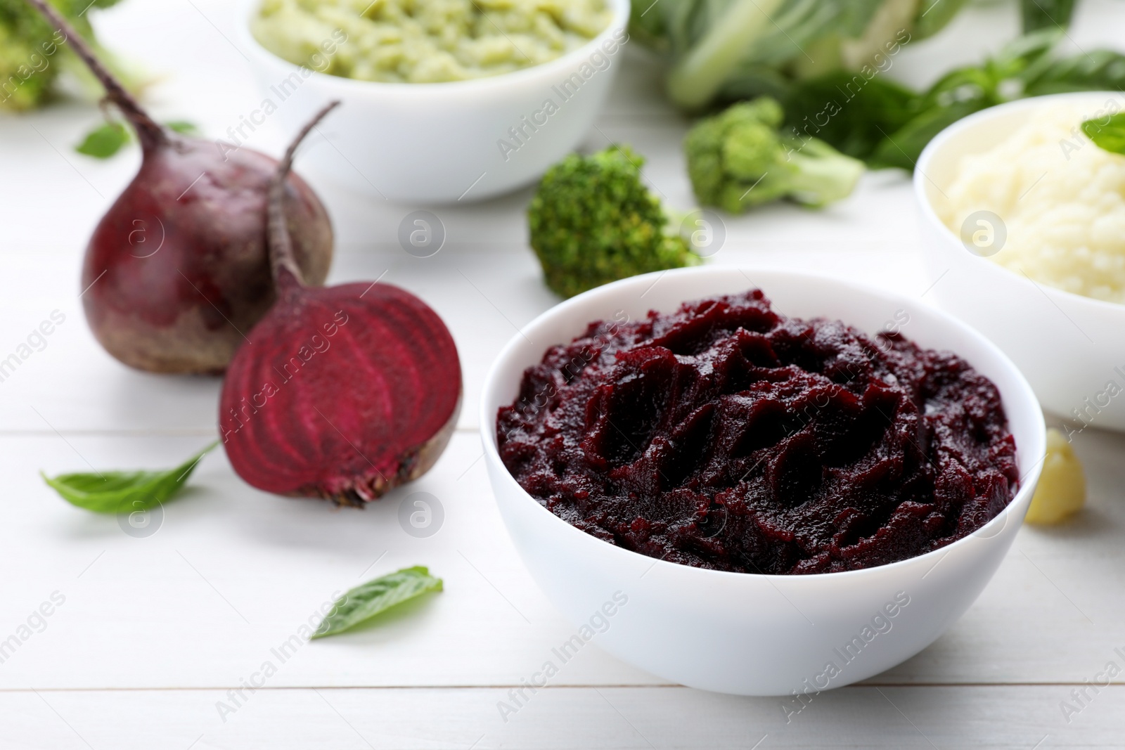 Photo of Bowl with tasty beet puree and ingredients on white wooden table