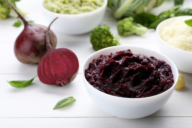 Bowl with tasty beet puree and ingredients on white wooden table