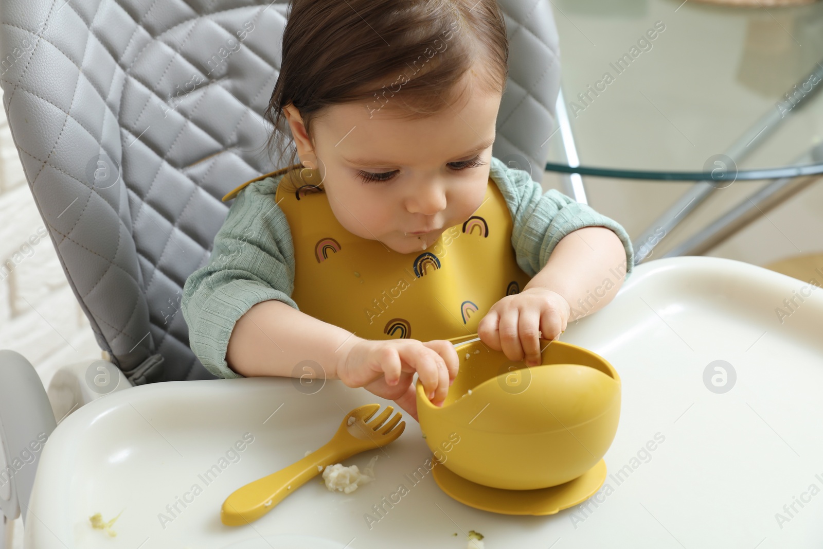 Photo of Cute little baby eating healthy food in high chair indoors