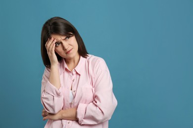 Photo of Young woman suffering from migraine on light blue background. Space for text