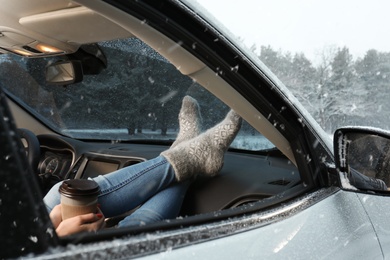 Photo of Young woman in warm socks resting inside car, closeup