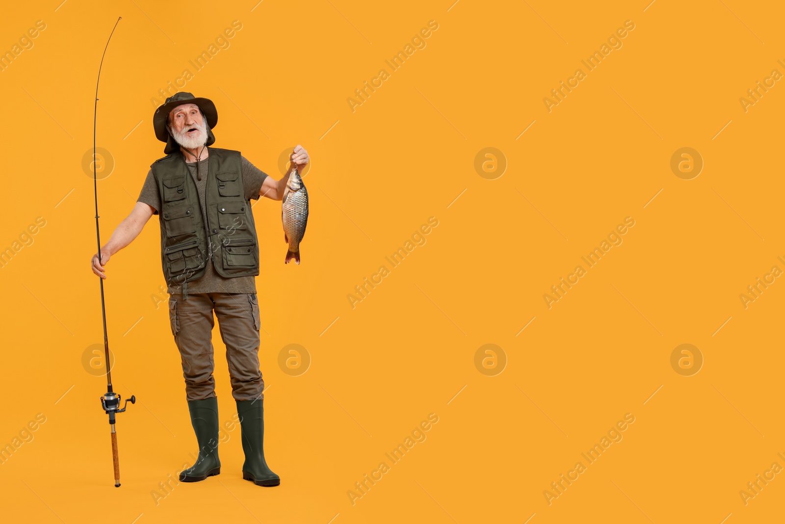 Photo of Fisherman with rod and catch on yellow background, space for text