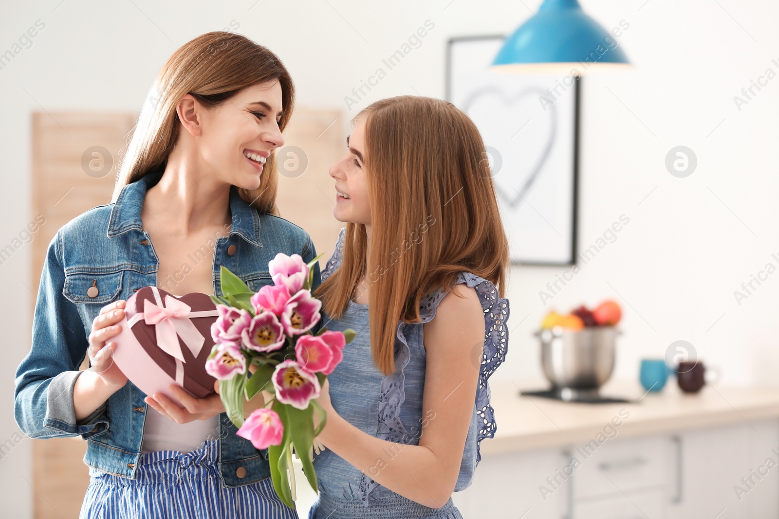 Photo of Teenage daughter congratulating happy woman on Mother's Day at home