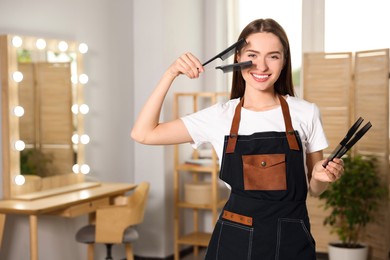 Photo of Portrait of happy hairdresser with combs in beauty salon