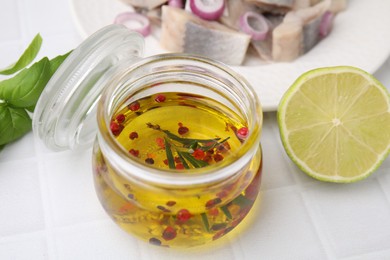 Tasty fish marinade in jar and lime on light tiled table, closeup